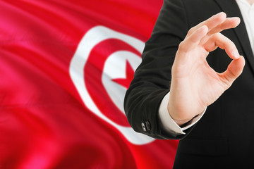 Wall Mural - Tunisia acceptance concept. Elegant businessman is showing ok sign with hand on national flag background.