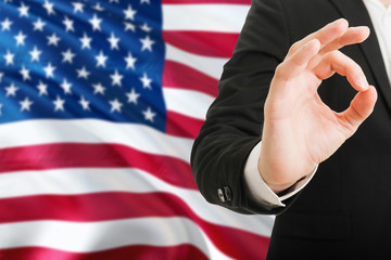 Wall Mural - United States acceptance concept. Elegant businessman is showing ok sign with hand on national flag background.