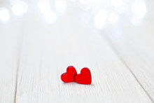 Two Small Red Wooden Hearts On A Light Wooden Background For Design For Valentine's Day. Image Of Happy Love. Blur. Copy Space