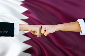 Wall Mural - Qatar agreement concept. Man and woman fist bumping on national flag to show cooperation. Peace and teamwork theme.