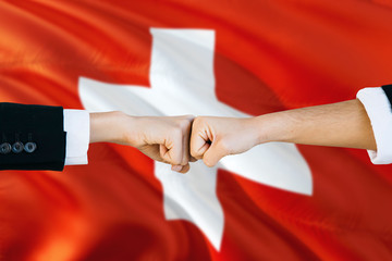 Wall Mural - Switzerland agreement concept. Man and woman fist bumping on national flag to show cooperation. Peace and teamwork theme.