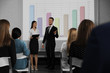 © New Africa - Business trainers giving lecture in conference room with projection screen