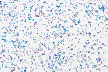 Wall Mural - glowing mica glitter confetti on white background. festive abstract backdrop. holiday flat lay.