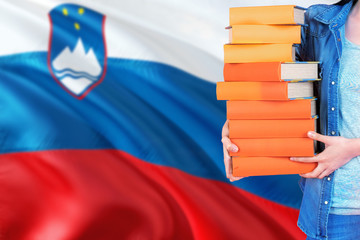 Slovenia national education concept. Close up of female student holding colorful books with country flag background.