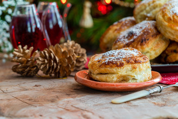 Wall Mural - Homemade Christmas puff pastry mince pies with Christmas tree in the background