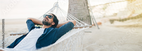 Fotografía A man enjoys calm, lies in a hammock on the background of the ocean and sunset