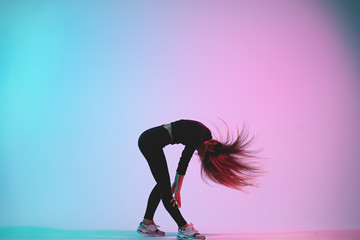 Handsome creative female dancer posing in studio against colorful background. Young charismatic woman dancing