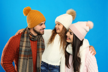 Wall Mural - Happy family in warm clothes on blue background. Winter vacation