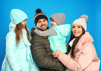 Wall Mural - Happy family in warm clothes on blue background. Winter vacation