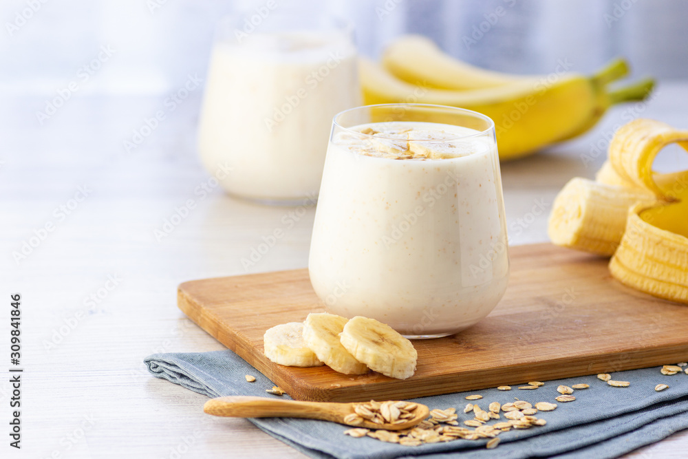 Vegan banana and oatmeal smoothie in glass jar on the light background. Healthy food.