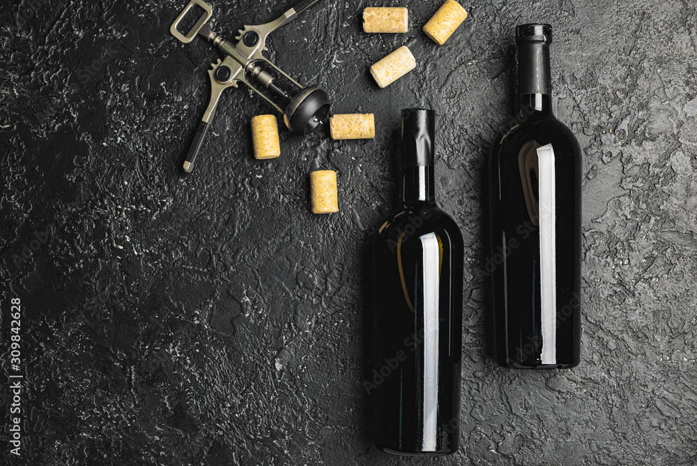 Bottles of tasty wine and corks on dark background