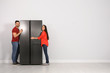 © New Africa - Young couple hugging refrigerator near light grey wall, space for text