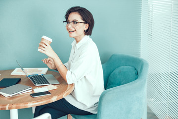 Happy lady is enjoying hot drink at workplace