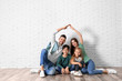 © New Africa - Happy family forming roof with their hands near brick wall. Insurance concept