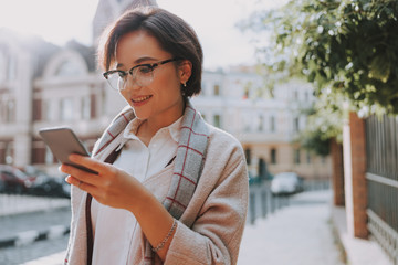 Smiling young woman is typing on phone