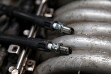 Canvas Print - Spark plugs with high voltage wires on the engine under the hood of a car during diagnosis and repair in a workshop for vehicles. Auto service industrial.