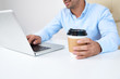 © DragonImages - Young entrepreneur drinking cup of take away coffee when working on laptop in office