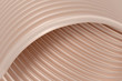 3D abstract background with a brown shade of peach cream, consisting of overlapping wavy ribbed surfaces, reminiscent of the texture of plastic or metal. Wallpaper for graphic design or cover art.