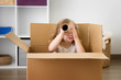 © Lisa Tichané - Funny portrait of young girl looking through cardboard tube while sitting in box