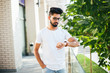 © F8  \ Suport Ukraine - Indian man posed outdoor and looking at his watches.