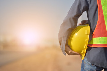 Wall Mural - Close up Engineering holding Yellow helmet hard hat safety and Road construction background