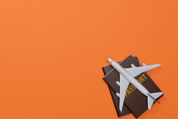 Creative flatlay of Traveler's accessories with passport and airplane toy isolated orange background with empty space,Tropical travel concept