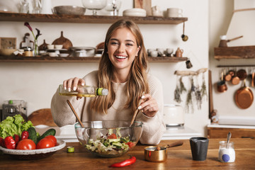 Image of joyful nice woman laughing while cooking dinner