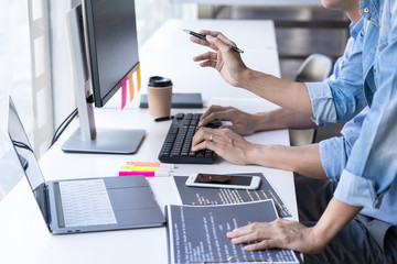 young startup programmers sitting at desks working on computers screen for developing programming an