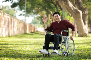 Asian Young Man sitting on the wheelchair in the park hospital