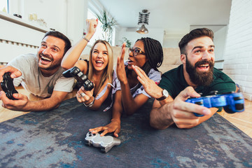 Happy multiethnic friends playing video game and having fun at home.