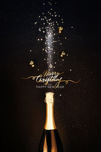 Festive Christmas Background. Bottle Of Champagne With A Spray Of Sparkles And Christmas Decorations. Happy New Year Concept