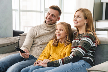 Sticker - Image of caucasian happy family watching television on sofa at home