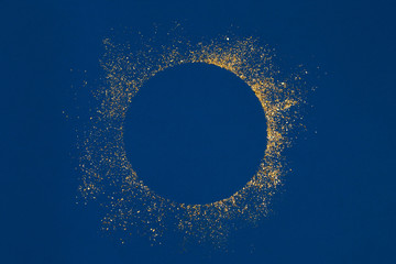 Circle gold glitter splash with empty center on blue background.