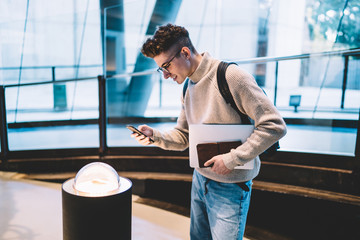 Student in glasses taking photo of exhibition lamp