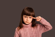 © Marharyta Hanhalo - Are you stupid? Little brunette girl child on a gray background shows a gesture twists a finger at the weight indicating the stupidity foolishness of the interlocutor