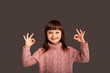 © Marharyta Hanhalo - Funny joyful child girl shows a cute gesture two hands up, in a playful way, says that she has everything super and shows OK with both hands