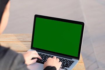 over should of woman using green screen laptop computer on sunny day. blur background