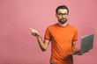 Image of a young optimistic handsome bearded man posing isolated over pink wall background wearing glasses using laptop computer pointing have an idea.