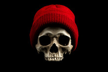 Human Skull Wearing Red Winter Hat Isolated On Black Background. Cold Weather Concept.