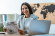 © LIGHTFIELD STUDIOS - attractive travel agent holding travel newspaper and looking at camera