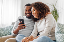 Technology, Internet And People Concept - Happy African American Couple With Smartphone At Home