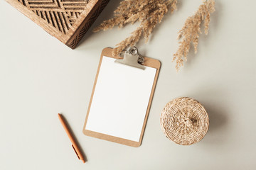 Wall Mural - Blank sheet clipboard with empty copy space, pen, rattan casket on neutral background. Flat lay, top view minimal business template for social media, magazine, blog. Home office desk table workspace.