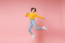 Funny Young Brunette Woman Girl In Yellow Sweater Posing Isolated On Pastel Pink Background In Studio. People Lifestyle Concept. Mock Up Copy Space. Having Fun Fooling Around, Looking Aside, Jumping.