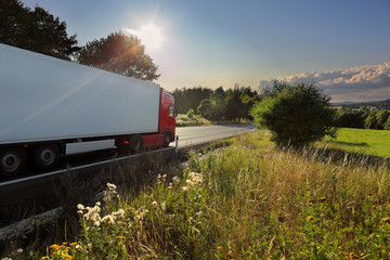 Red truck transport on the road and cargo at sunset