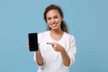 African american doctor woman isolated on blue background. Female doctor in medical gown pointing on mobile phone with blank empty screen. Healthcare personnel medicine concept. Mock up copy space.