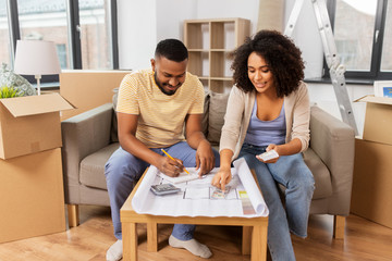 Wall Mural - mortgage, moving and real estate concept - happy african american couple with blueprint and calculator counting money for repair costs to new home