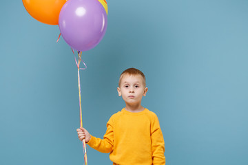 Wall Mural - Little cute kid boy 4-5 years old have fun celebrating birthday holiday party with colorful air balloons isolated on pastel blue wall background. People sincere emotions, childhood lifestyle concept.