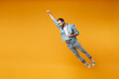 Funny young bearded man in casual blue shirt posing isolated on yellow orange background, studio portrait. People lifestyle concept. Mock up copy space. Jumping with outstretched hand like Superman.