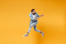 Funny Young Bearded Man In Casual Blue Shirt Posing Isolated On Yellow Orange Background, Studio Portrait. People Emotions Lifestyle Concept. Mock Up Copy Space. Jumping Pointing Index Fingers Aside.