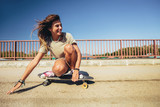 Young sporty woman riding on the skateboard on the road.